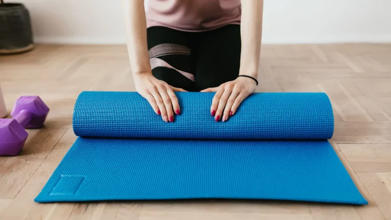 Personne déroulant un tapis bleu pour préparer une séance de sport à domicile.